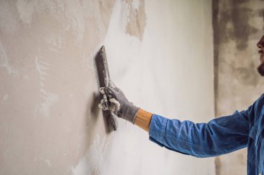 Genç ana duvarda beyaz macun uygulama ve gündüzleri ev tadilatı Oda macun bıçak ile bulaşması.