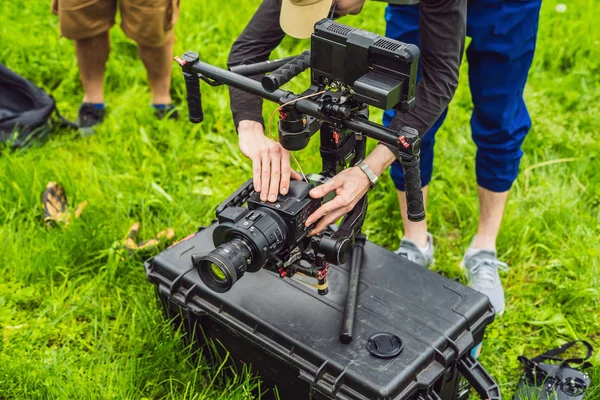 Cameraman setting up heavy duty professional 3-axis gimbal stabilizer for cinema camera — Stock Photo, Image