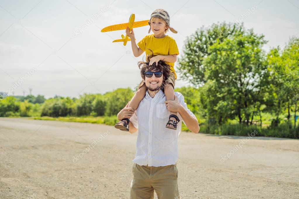 Happy father and son playing with toy airplane in countryside