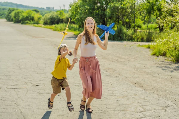 Felice madre e figlio che giocano con aereo giocattolo sullo sfondo della vecchia pista. Viaggiare con il concetto di bambini — Foto Stock