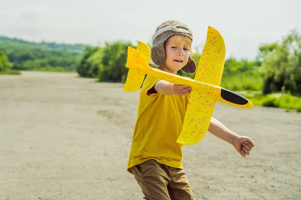Счастливый ребенок играет с игрушечным самолетом на фоне старой взлетно-посадочной полосы. Путешествие с детьми концепция — стоковое фото