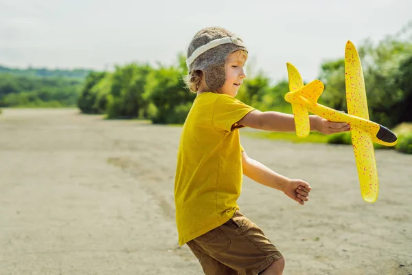 Gelukkig kind spelen met speelgoed vliegtuig tegen oude baan achtergrond. Reizen met kids concept — Stockfoto