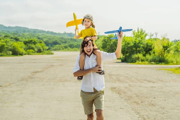 Buon padre e figlio che giocano con l'aeroplano giocattolo sullo sfondo della vecchia pista. Viaggiare con il concetto di bambini — Foto Stock