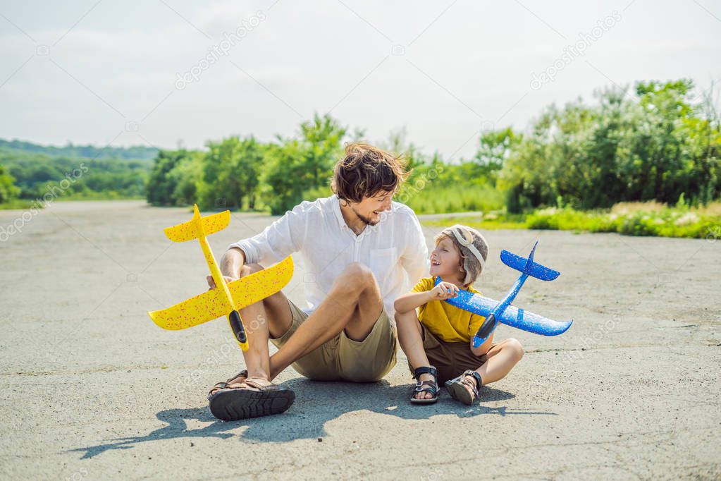Happy father and son playing with toy airplane against old runway background. Traveling with kids concept