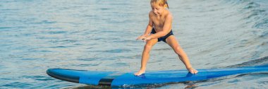 Küçük çocuk tropik sahilde sörf. Sörf tahtası dalga okyanus üzerinde çocuk. Çocuklar için etkin su sporları. Yüzme sörf ile evlat. Sörf dersi için kids afiş, uzun biçimde
