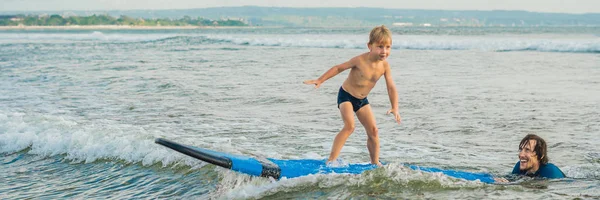 Батько або інструктор навчають свого 4-річного сина, як серфінгувати в морі у відпустці або на відпочинку. Подорожі та спорт з дитячою концепцією. Серфінг-урок для дітей BANNER, LONG FORMAT — стокове фото
