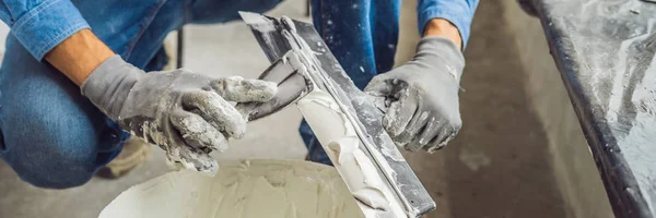 Mestre está aplicando massa de vidraceiro branco em uma parede e manchando por faca de vidraceiro em uma sala de renovação da casa durante o dia BANNER, LONG FORMAT — Fotografia de Stock