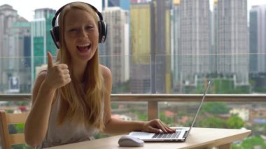 Genç kadın serbest meslek sahibi balkon şehir merkezinin arka plan ile dizüstü bilgisayarda çalışırken kabul.