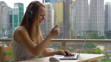 Genç kadın serbest meslek sahibi balkon şehir merkezinin arka plan ile dizüstü bilgisayarda çalışırken kabul.