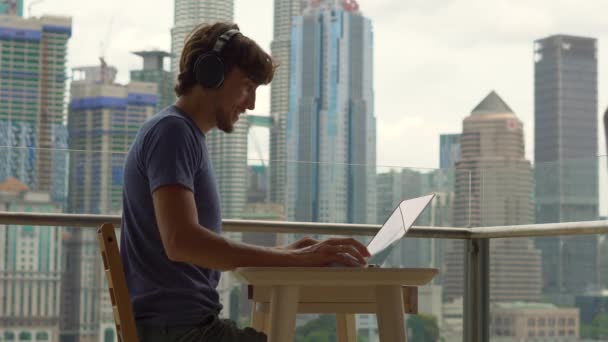 Joven Freelancer Masculino Sonriendo Mientras Trabaja Portátil Balcón Con Fondo — Vídeo de stock