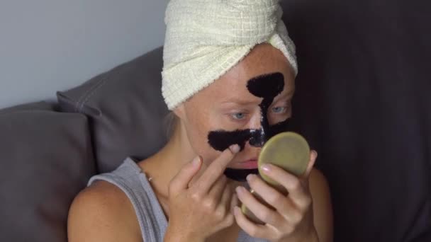 Schöne Junge Frau Anwendung Schwarzer Gesichtsmaske — Stockvideo