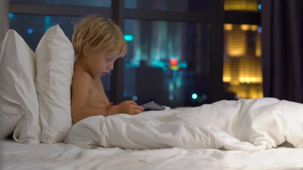 Kleiner Blonder Junge Sitzt Nachts Bett Und Spielt Digitales Tablet — Stockvideo