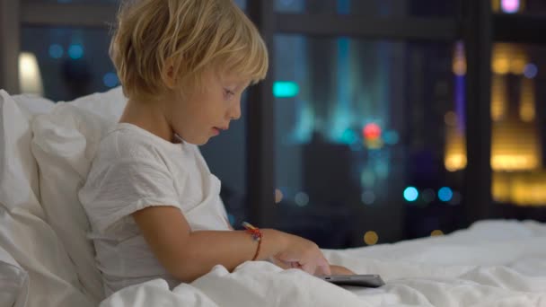 Pequeño Niño Rubio Sentado Cama Por Noche Jugando Tableta Digital — Vídeo de stock