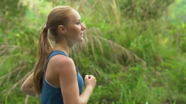 Steadicam tiro de uma jovem mulher correndo em um parque tropical — Vídeo de Stock