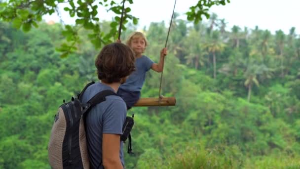 父亲在热带公园荡秋千小儿子的慢动作镜头 — 图库视频影像