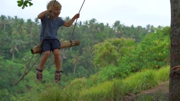 Lento Tiro Movimento Jovem Empurrando Pequeno Filho Oscilações Parque Tropical — Vídeo de Stock