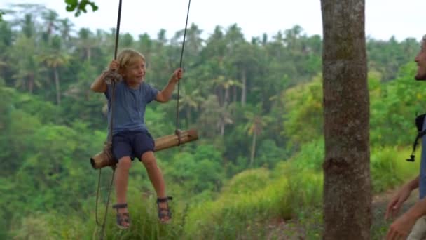 父熱帯公園でブランコに幼い息子をスイングのスローモーション撮影 — ストック動画