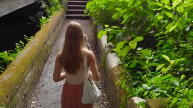 Ağır çekim Genç kadın ve küçük oğlu dolaşan Ubud tapınakta Pura Gunung Lebah üzerinde Bali Adası, Endonezya