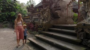 Ağır çekim Genç kadın ve küçük oğlu dolaşan Ubud tapınakta Pura Gunung Lebah üzerinde Bali Adası, Endonezya