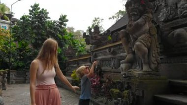 Ağır çekim Genç kadın ve küçük oğlu dolaşan Ubud tapınakta Pura Gunung Lebah üzerinde Bali Adası, Endonezya