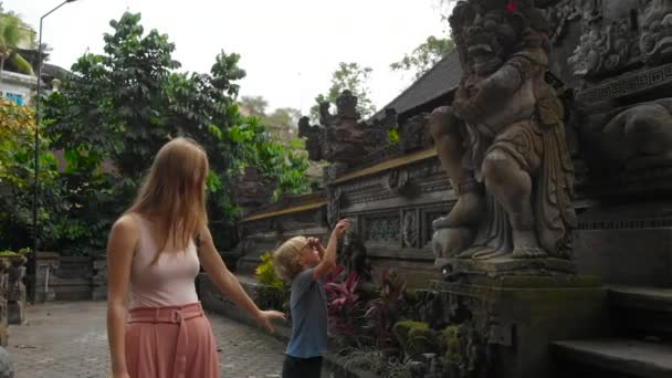 若い女性とインドネシア バリ島ウブドのプラ グヌン Lebah 寺院を歩いての幼い息子のスローモーション — ストック動画