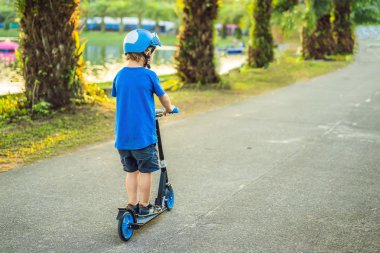 Parkta bir scooter sürme bir kask içinde bir oğlan