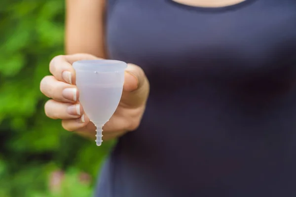 Manos de mujer joven sosteniendo diferentes tipos de productos de higiene femenina: copa menstrual y tampones — Foto de Stock