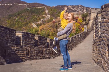 Happy cheerful joyful tourists mom and son at Great Wall of China having fun on travel smiling laughing and dancing during vacation trip in Asia. Chinese destination. Travel with children in China clipart
