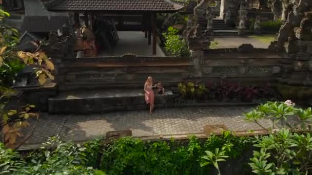 Letecký snímek rodiny cestující sedí na schodech chrámu Pura Gunung Lebah v Ubudu na ostrově Bali — Stock video
