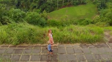 Genç bir kadın ve küçük oğlu sanatçı Walk - Campuhan Ridge yürümek Ubud köyün Bali Adası üzerinde yürüyen hava atış