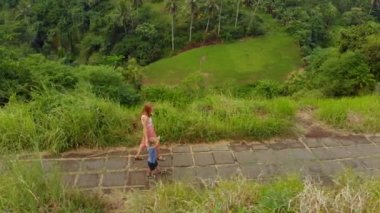 Genç bir kadın ve küçük oğlu sanatçı Walk - Campuhan Ridge yürümek Ubud köyün Bali Adası üzerinde yürüyen hava atış
