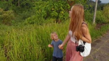 Genç bir kadın ve küçük oğlu sanatçı Walk - Campuhan Ridge yürümek Ubud köyün Bali Adası üzerinde yürüyen Steadicam atış
