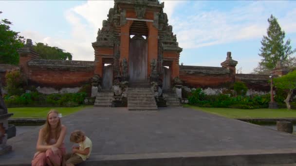 Slowmotion steadicam tourné d'une jeune femme et son petit fils visitant le palais royal Taman Ayun sur l'île de Bali — Video