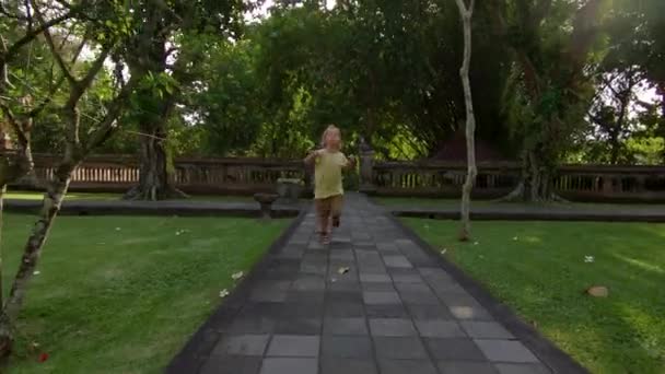 Zeitlupen-Steadicam-Aufnahme einer jungen Frau und ihres kleinen Sohnes beim Besuch des königlichen Palastes Taman Ayun auf der Insel Bali — Stockvideo