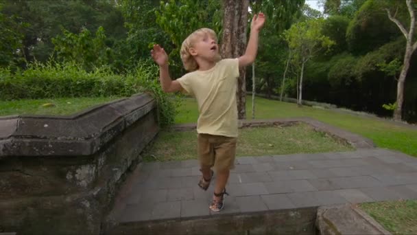 Slowmotion shot of a little boy jumping and making a 180 degree rotation — Stock Video