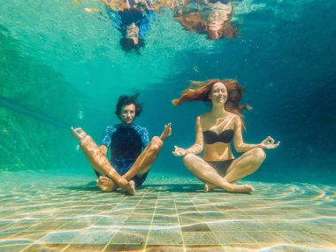 Genç kadın siyah bikini ve adam yoga konumda sualtı dalış akvaryum, tam vücut shot, önden görünüm.