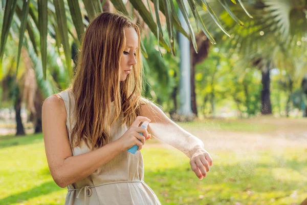 Женщина распыляет средство от насекомых на кожу снаружи — стоковое фото
