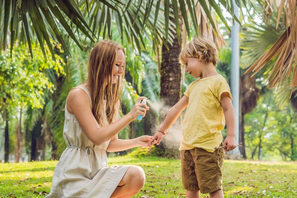 Mamma e figlio usano lo spray per zanzariere. Spruzzando repellente per insetti sulla pelle all'aperto — Foto Stock