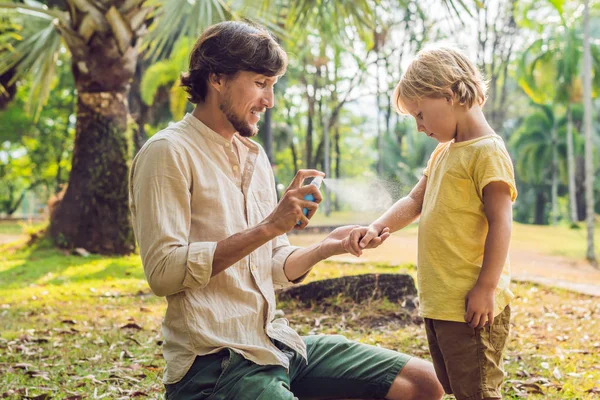 Papà e figlio usano lo spray per zanzariere. Spruzzando repellente per insetti sulla pelle all'aperto — Foto Stock