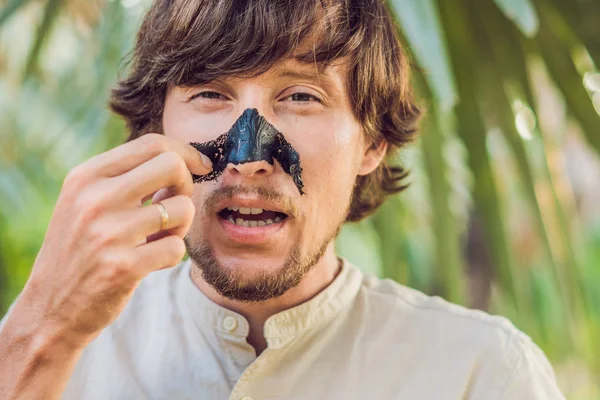 Uomo felice con la maschera nera sul viso. Foto dell'uomo che riceve trattamenti termali. Beauty concetto di cura della pelle — Foto Stock