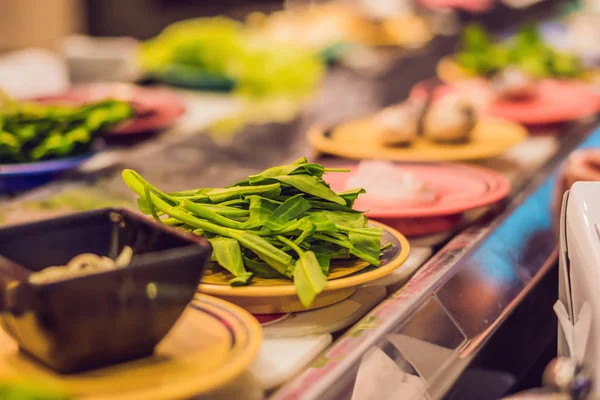 Bir kafede tabaklarda çiğ gıda ile bir konveyör