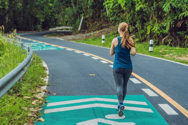 Deportiva corriendo por la carretera al amanecer. Fitness y entrenamiento concepto de bienestar — Foto de Stock