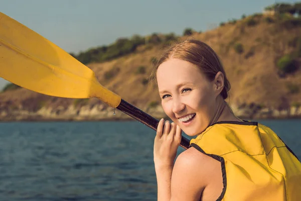 Una giovane donna sorridente che fa kayak in mare. Giovane donna felice in canoa in mare in una giornata estiva — Foto Stock
