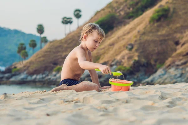 Niño jugando en la orilla del mar con pala y cubo — Foto de Stock