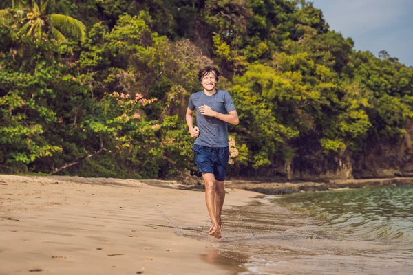 Молодой мужчина тренируется на пляже, спортивный человек делает упражнения — стоковое фото