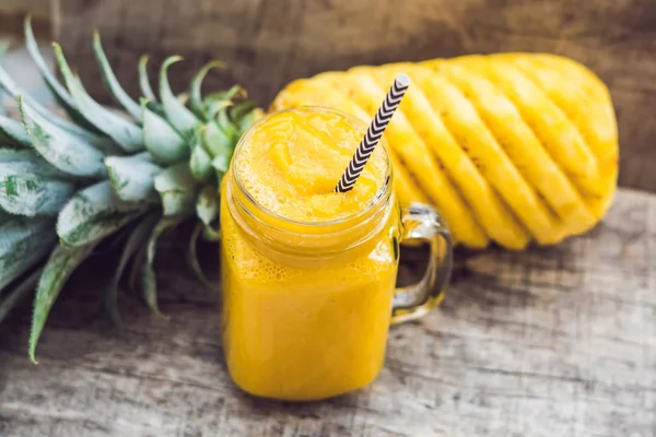 Pineapple smoothie with fresh pineapple on wooden table