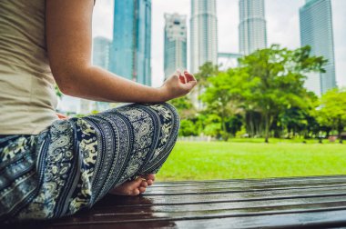 Gökdelenlerin arka planında meditasyon yapan genç bir kadın.