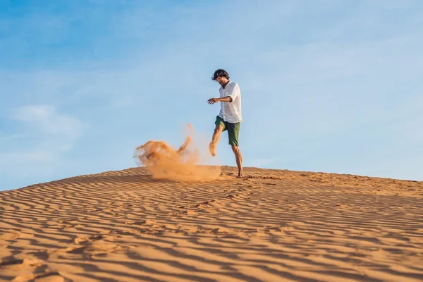 A man is kicking sand in a red desert. Splash of anger concept — Stock Photo, Image