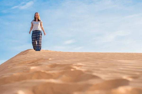 Fiatal nő rad homokos sivatagban naplementekor — Stock Fotó