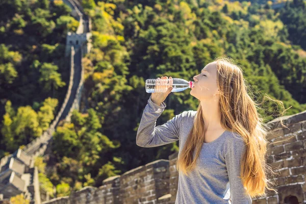 Feliz alegre alegre turista mujer en la Gran Muralla de China beber agua en viaje de vacaciones en Asia. Chica visitando y turismo destino chino — Foto de Stock